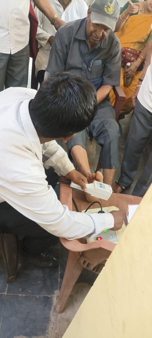 A health worker conducting a bone density test on a seated attendee while others wait